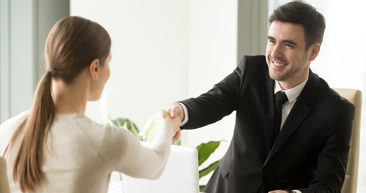 Hombre y mujer estrechando las manos luego de firmar un certificado parcelario