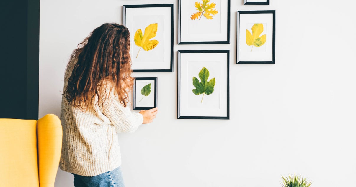 Mujer decorando una pared con cuadros