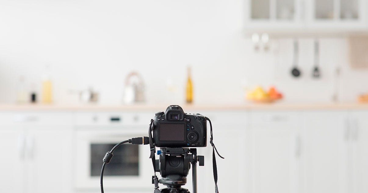 Imagen de sesión fotográfica inmobiliaria con una cámara fotográfica en el centro y de fondo una cocina
