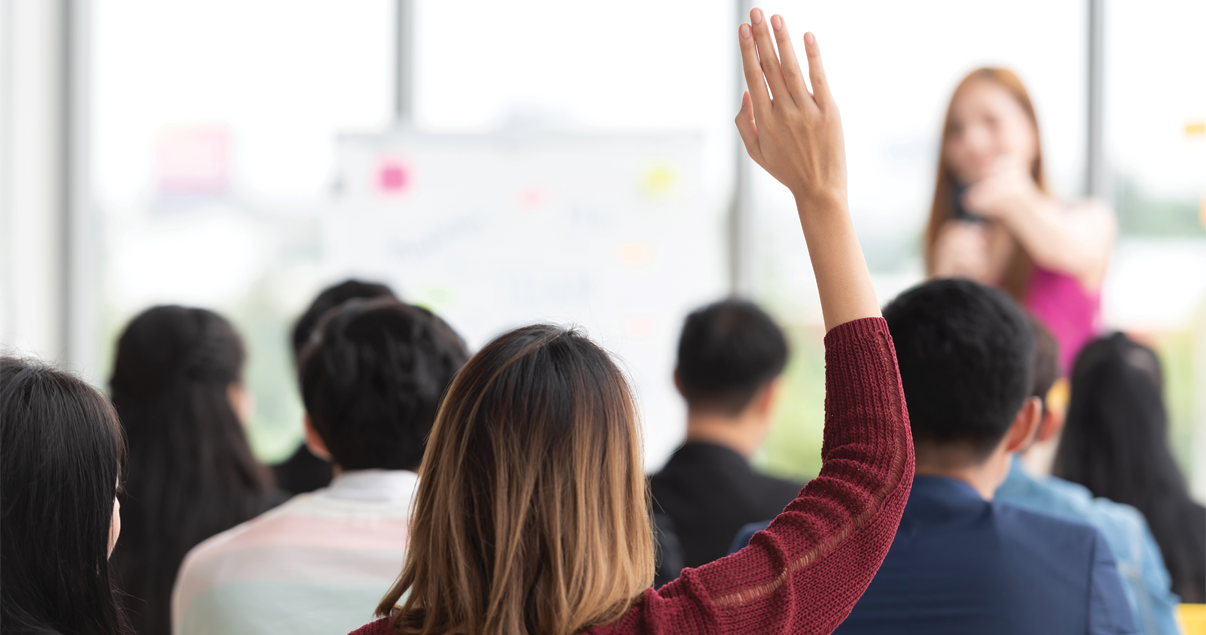 Mujer levantando la mano en una clase porque tiene dudas