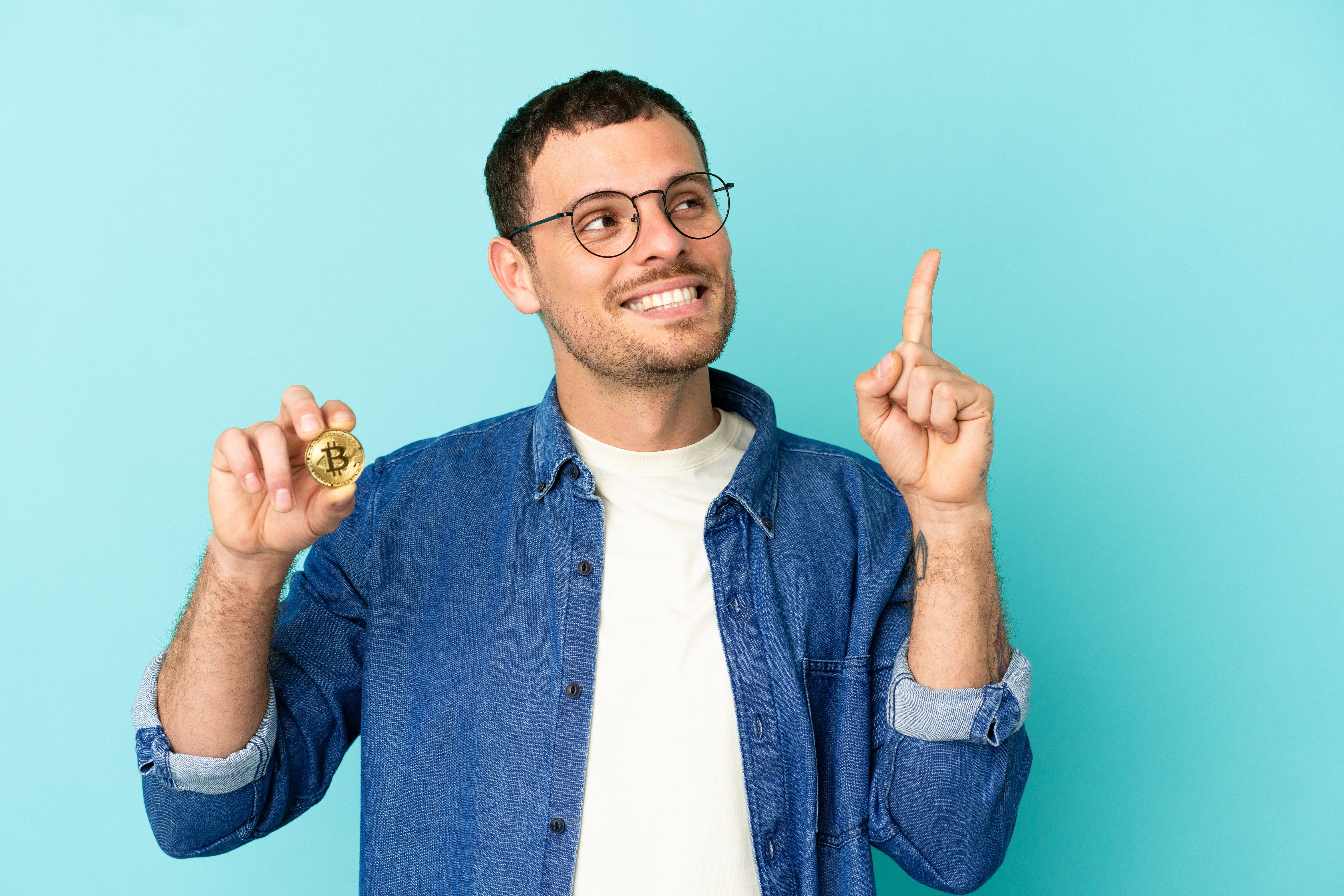 Hombre sentado mostrando una moneda de bitcoin